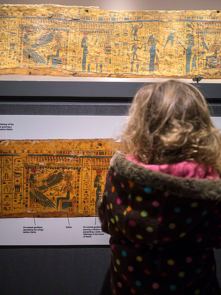 A young girl looking at a section of coffin