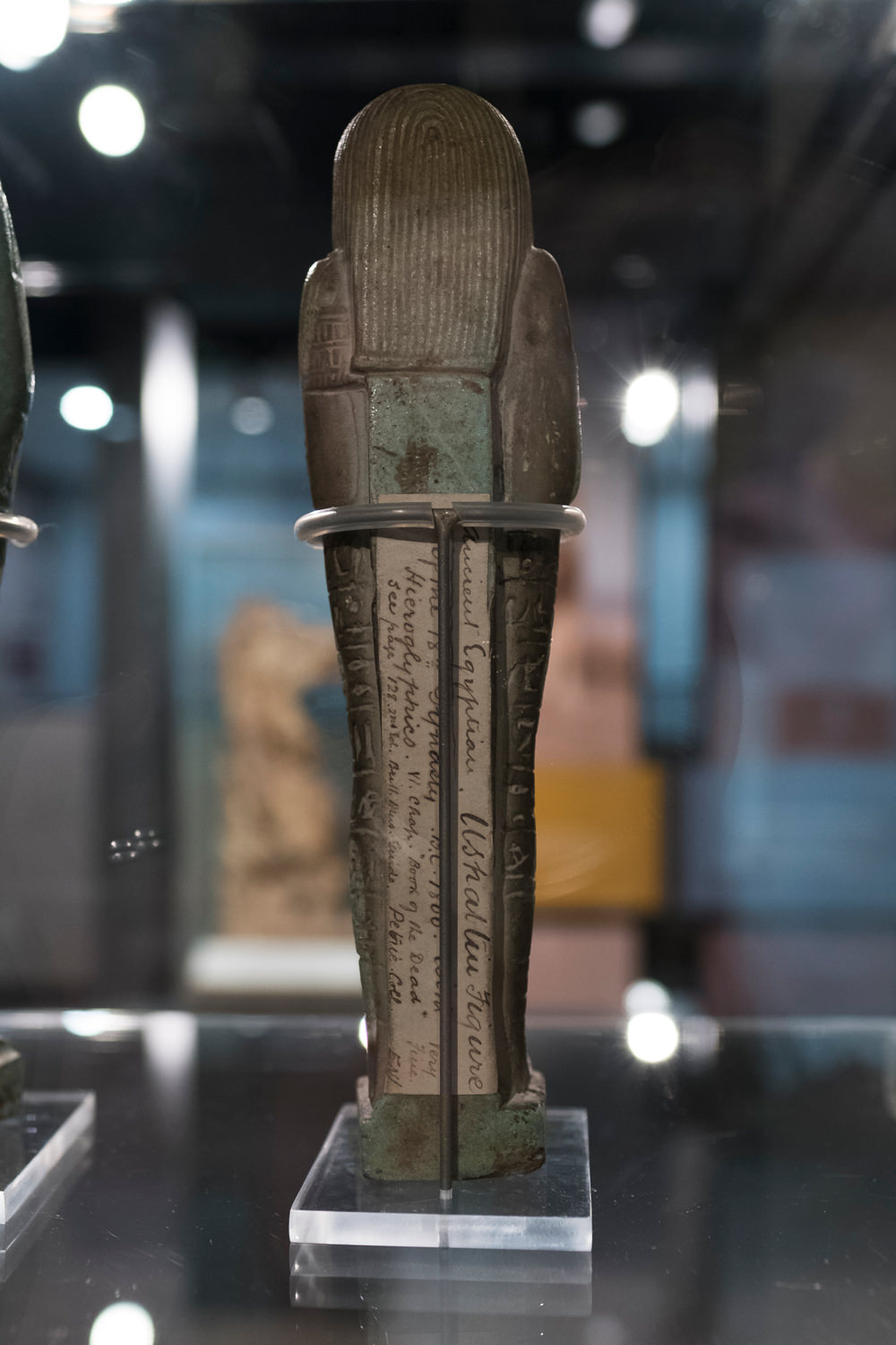 A shabti viewed from the back. It has an old, handwritten label in beautiful cursive script, from many years ago