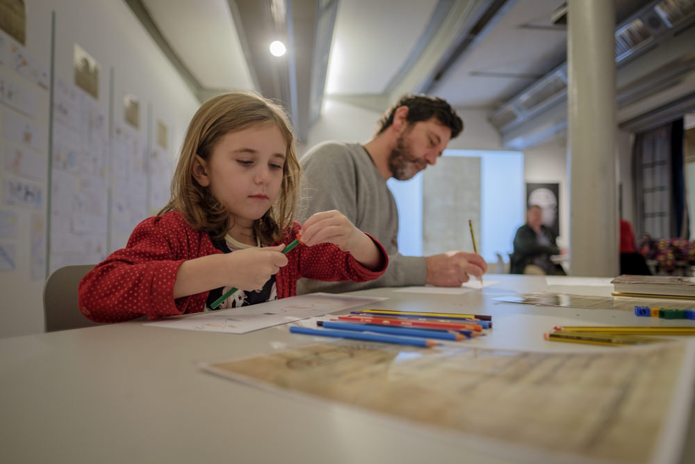 A father and daughter sitting at a table, drawing