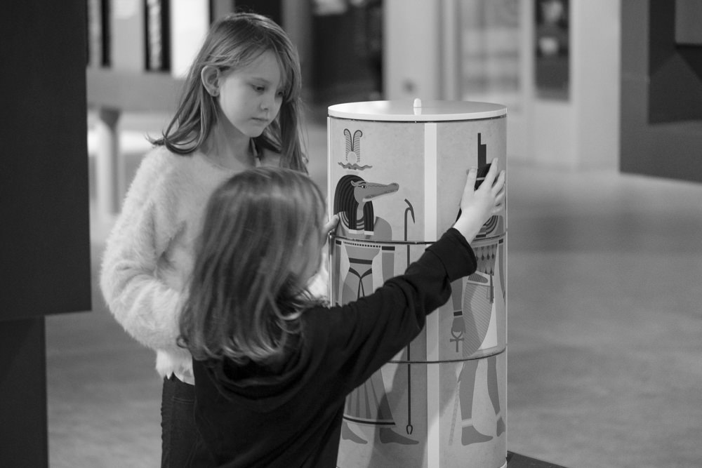 Two girls making Egyptian gods in a museum gallery