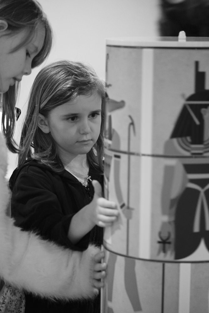 Two girls making Egyptian gods in a museum gallery