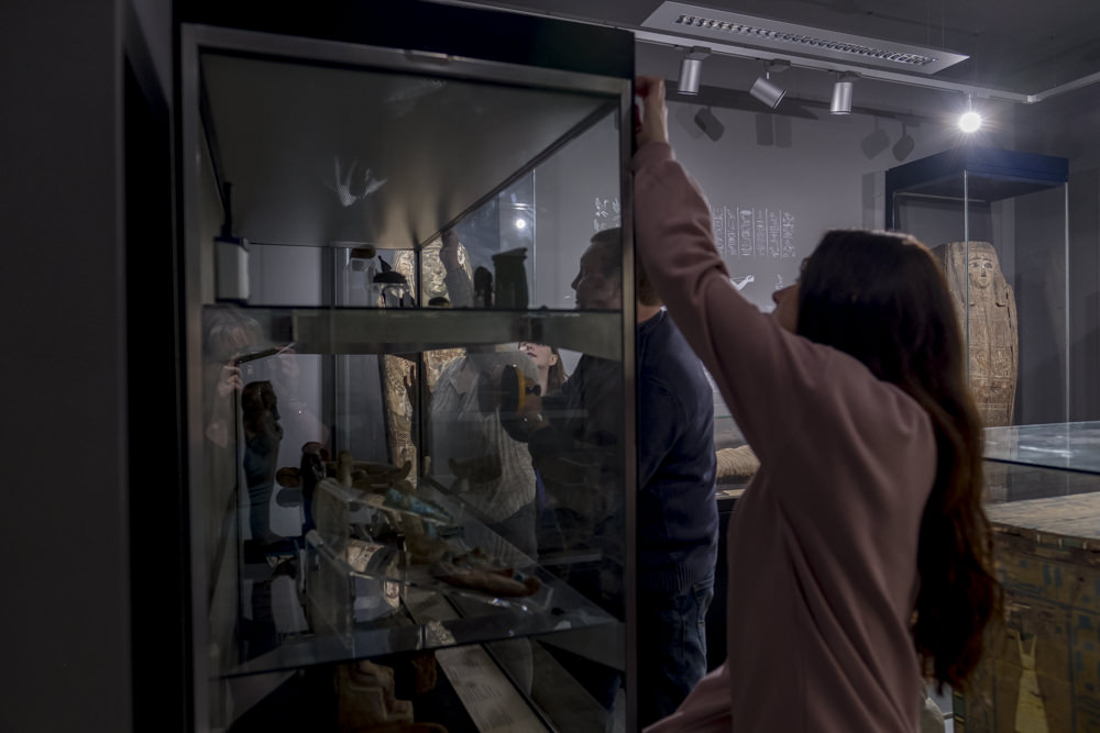 Four people in a museum gallery removing the glass from the front of a display case