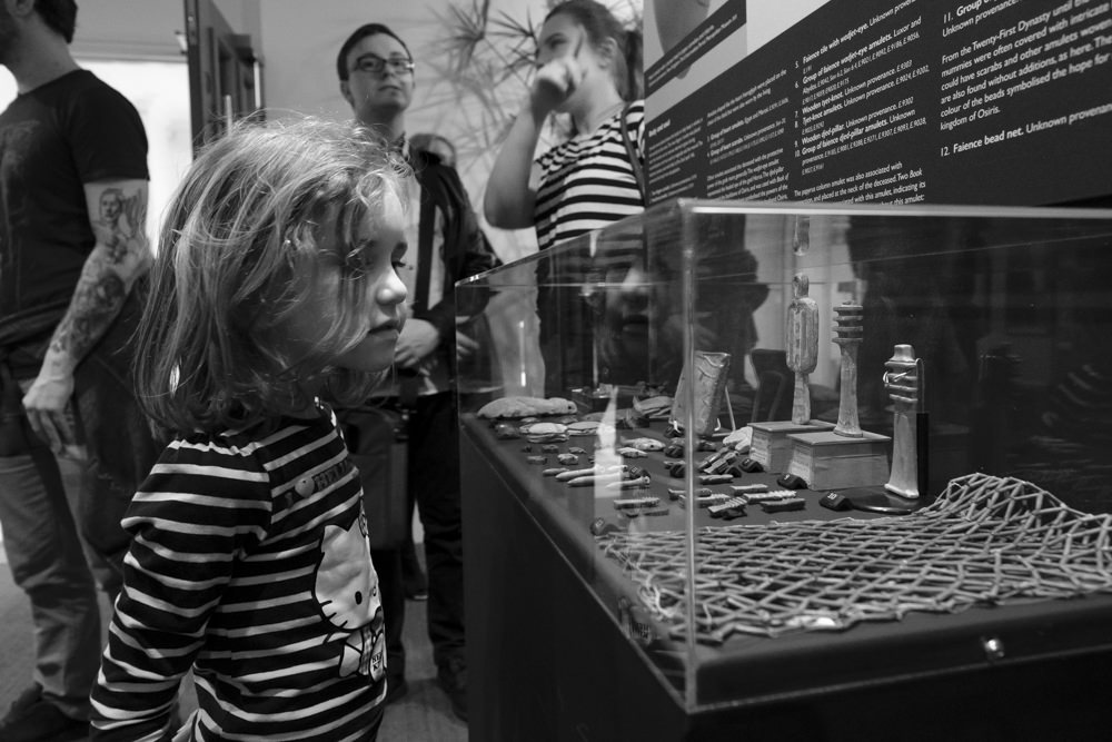 A girl looking at a display case of ancient Egyptian amulets