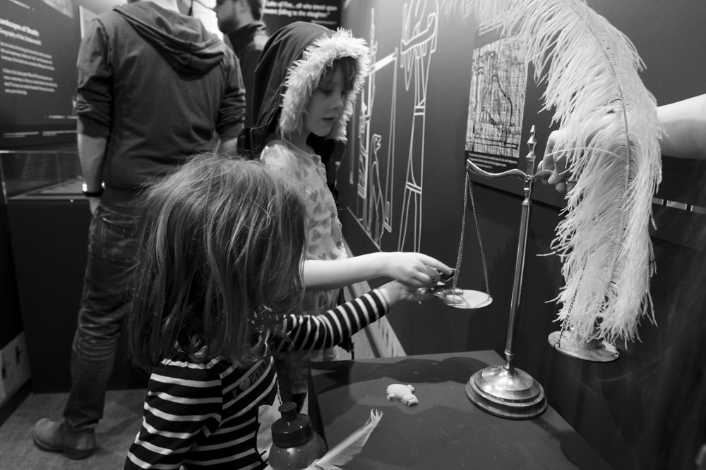 Two children playing with a set of scales, pretending to weigh their hearts in the Egyptian afterlife