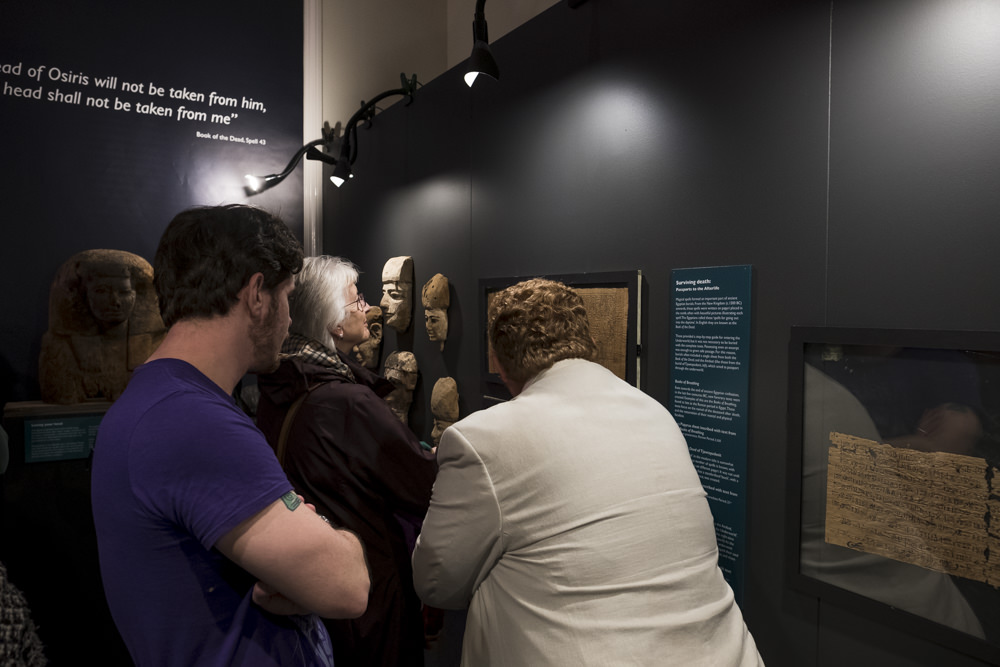 People looking at a sheet of ancient egyptian papyrus on display