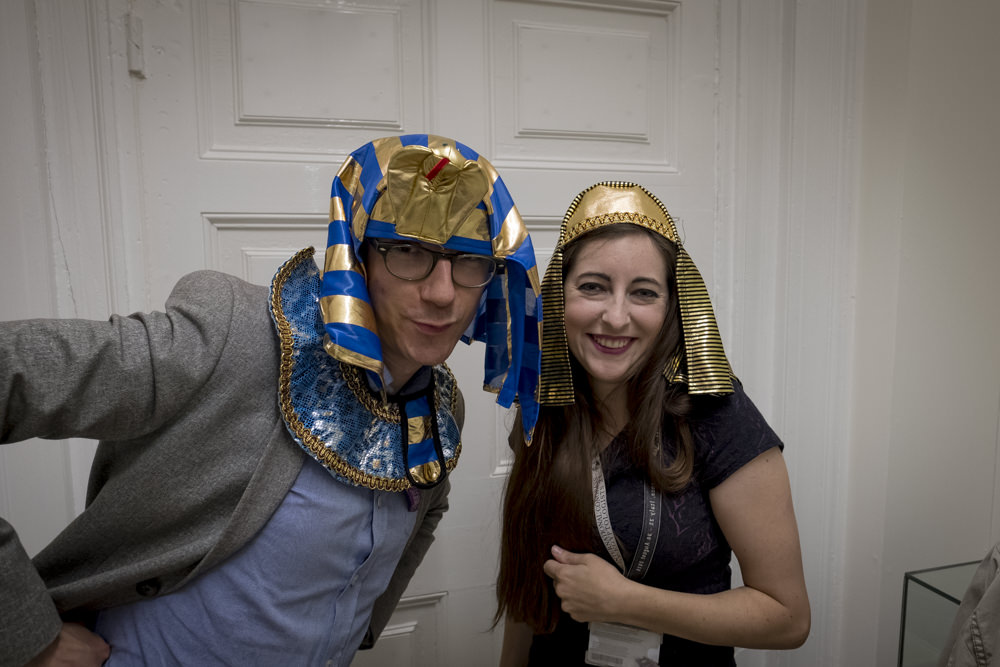 Two very grown-up Egyptologists wearing children's dress-up pharaoh's headdresses