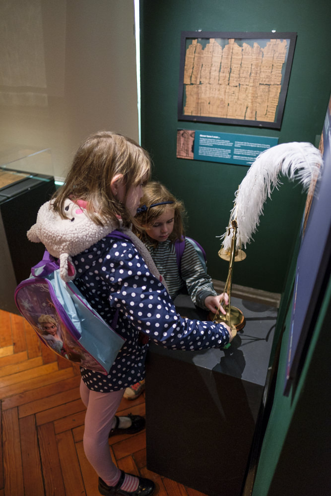 Two girls playing with a set of scales made to look like the ancient Egyptian scales of truth