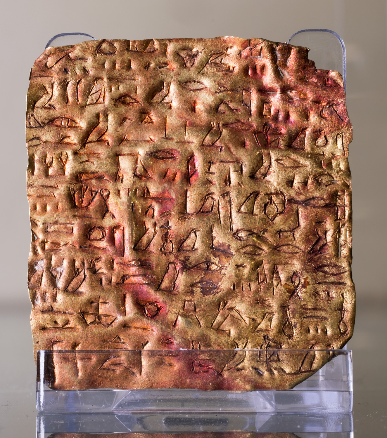 A small, gold ancient Egyptian plaque inscribed with hieroglyphs