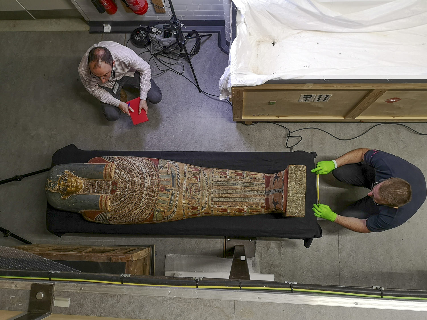 two men moving an egyptian coffin in a museum