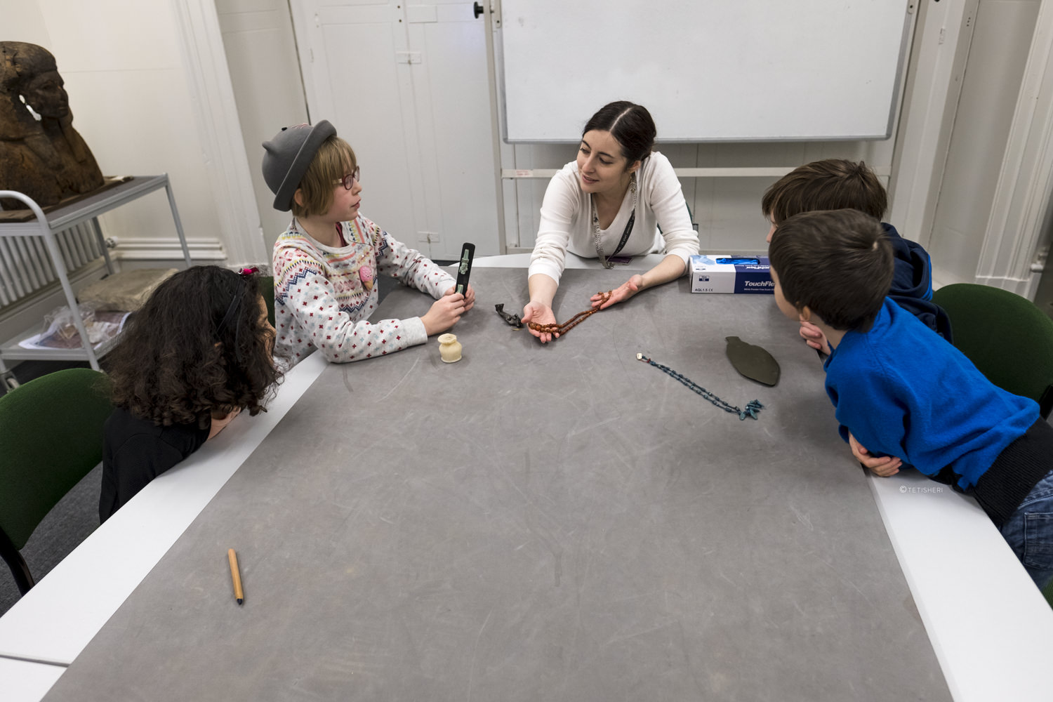 a curator with children looking at egyptian artefacts