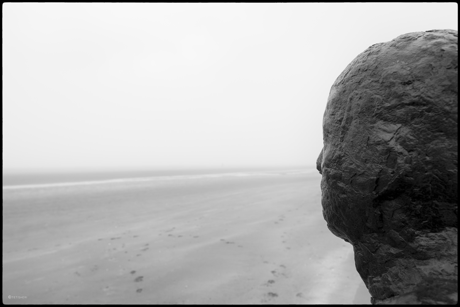 the back of the head of one of anthony gormley's another place statues on crosby beach