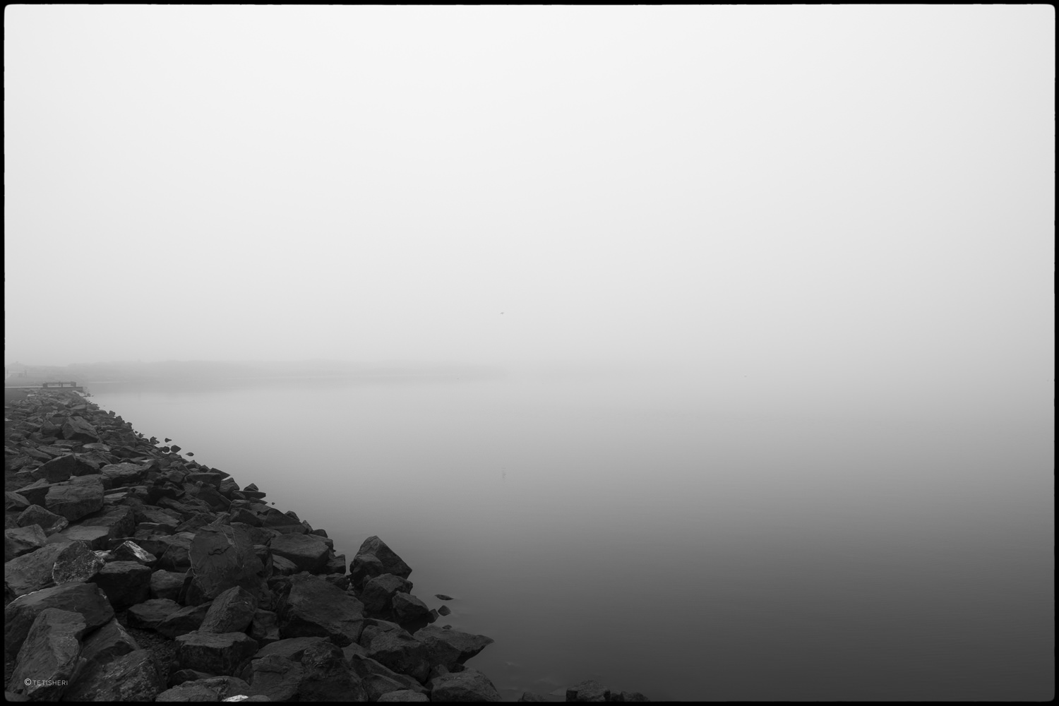 a lake surrounded by rocks shrouded in fog
