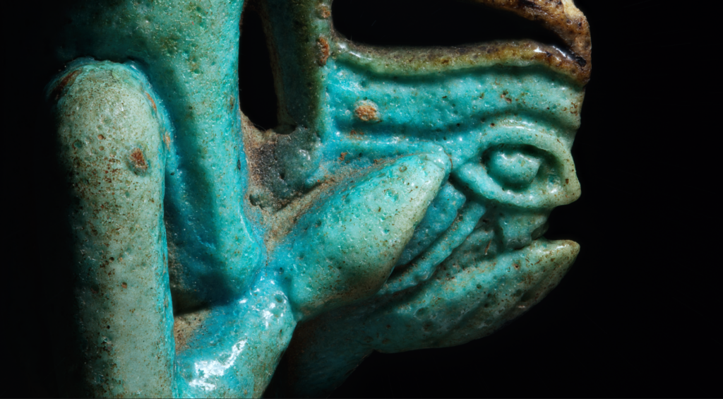 Close up of the side of the amulet showing the wadjet-eye and hands.