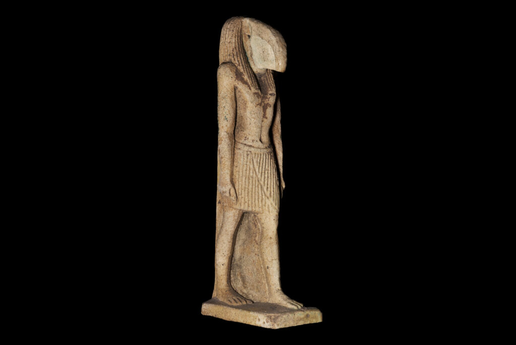 A standard amulet of Thoth as a human man wearing just a kilt with the head of an ibis and a traditional Egyptian wig. He stands in a striding pose with his hands by his sides.