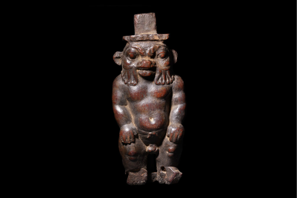 a wooden figurine of Bes as a front-facing dwarf with a beard.