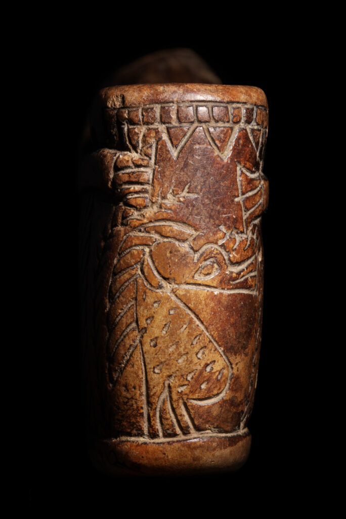 The side of an ancient Egyptian small, tubular pot with the goddess Taweret inscribed.