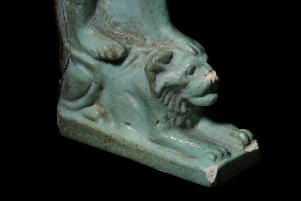 The bottom of an ancient Egyptian amulet of Nefertem showing his feet standing on a recumbant lion.