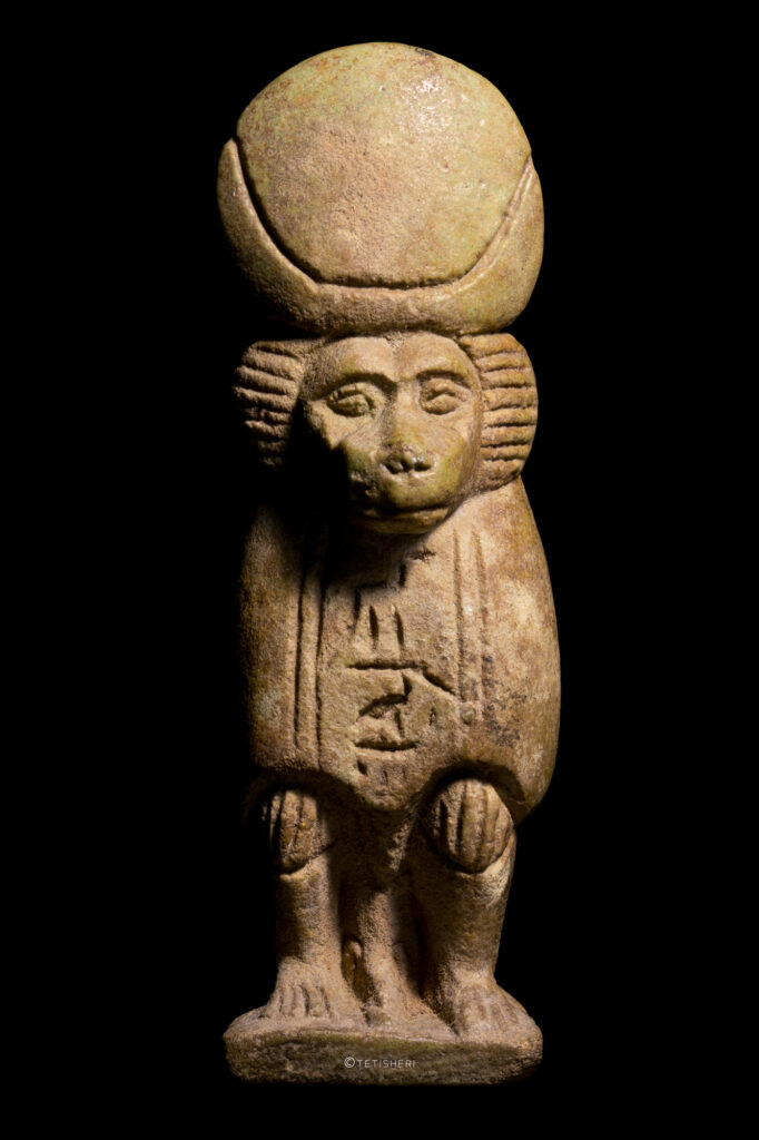 An amulet of the god Thoth in his form as a baboon. He has a sundisk and crescent moon headdress.