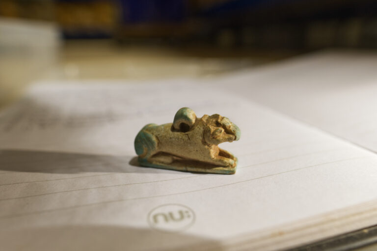 A small faience Egyptian amulet of a ram-headed sphinx.